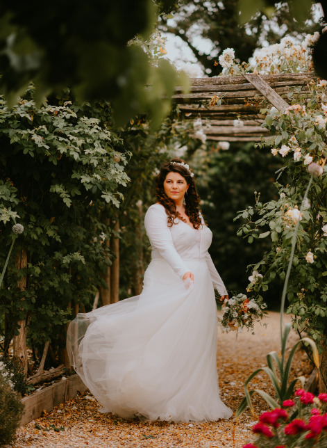 Bride in lace gown dancing under a garden arch